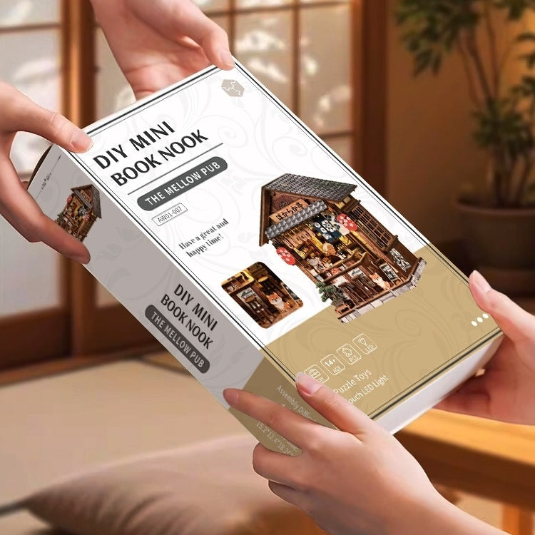 DIY mini book nook packaging held by hands with a warm indoor setting.