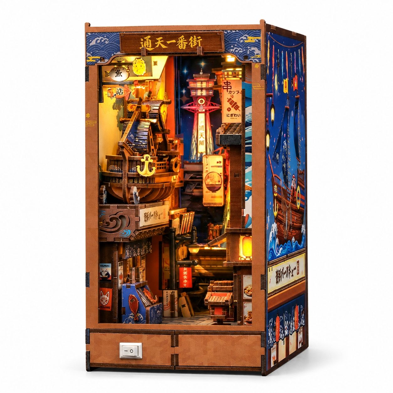 A detailed wooden miniature book nook with Japanese street and harbor scenes, featuring a ship, lanterns, buildings, and decorative panels, shown on a plain white background.