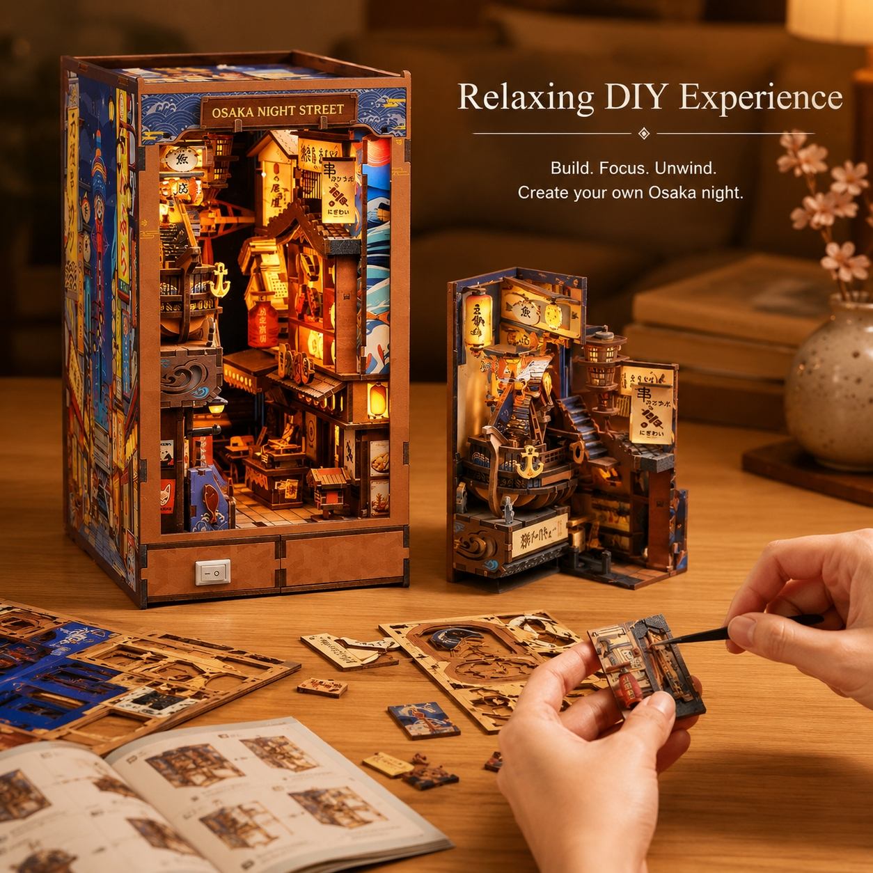 A wooden DIY model kit labeled 'Osaka Night Street' shown in its assembled box, alongside an opened instruction booklet and hands assembling smaller wooden pieces on a wooden table. The scene is warmly lit and includes the text 'Relaxing DIY Experience' and 'Build.