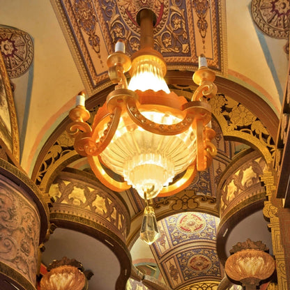 Decorative miniature vintage Baroque chandelier hanging from a ornate ceiling with intricate designs.