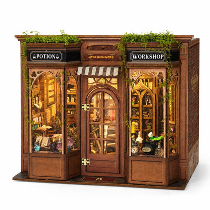 A miniature wooden diorama of a wizarding shop front with 'POTION' on the left and 'WORKSHOP' on the right, featuring detailed interior scenes, glass windows, and green ivy accents.