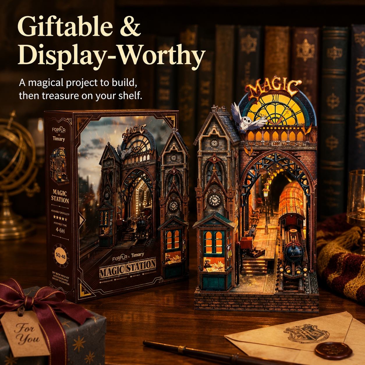 A magic-themed Magic Station 3D model kit displayed next to its retail box on a wooden table, with Hogwarts bookshelves in the background and themed props including a wrapped gift, wand, and letter.