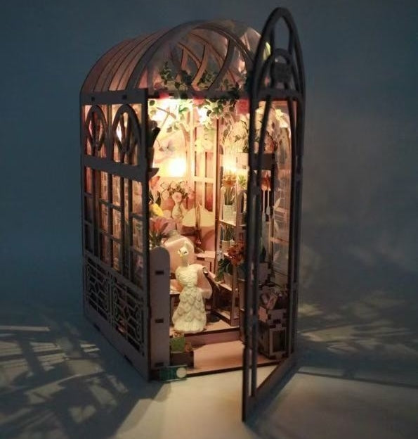 image displaying Mini Greenhouse DIY Book Nook Kit casting warm light