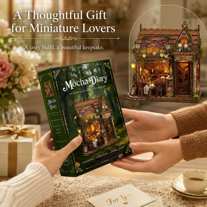 A person holds a green Mocha Diary miniature book in both hands, with a beautifully lit miniature fairy house displayed in a circular inset. The scene is set in a cozy, warm-toned room with a gift box and a cup of tea on the table, under the text 'A Thoughtful Gift for Miniature Lovers'.