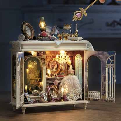 Decorative miniature scene with a chandelier, crown, and other ornaments inside a cabinet.