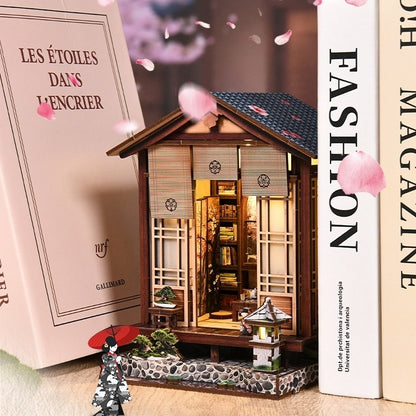 Miniature Japanese-style house with cherry blossoms and books in the background