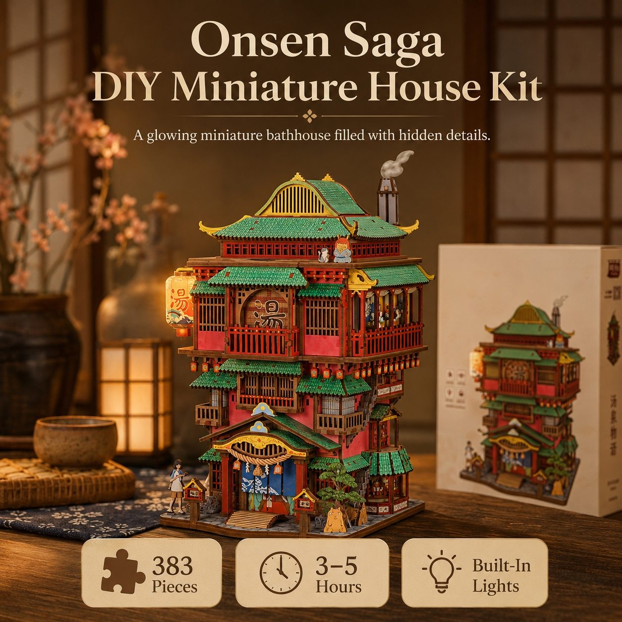 Onsen Saga DIY Miniature House Kit shown assembled on a wooden table with its retail box beside it. The kit features a detailed miniature Japanese-style bathhouse structure with red and green roofs, lit warm interior lights, and small decorative figures.