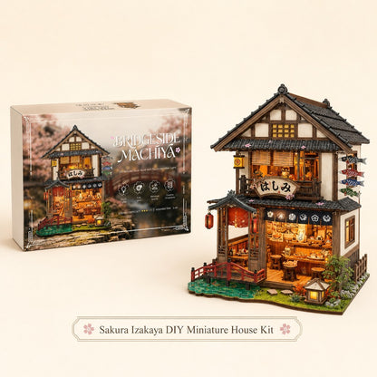 Sakura Izakaya DIY miniature house kit shown next to its retail packaging box on a warm beige background. The kit features a detailed, multi-story Japanese-style tea house with glowing warm interior lights, a red bridge, and decorative signs.