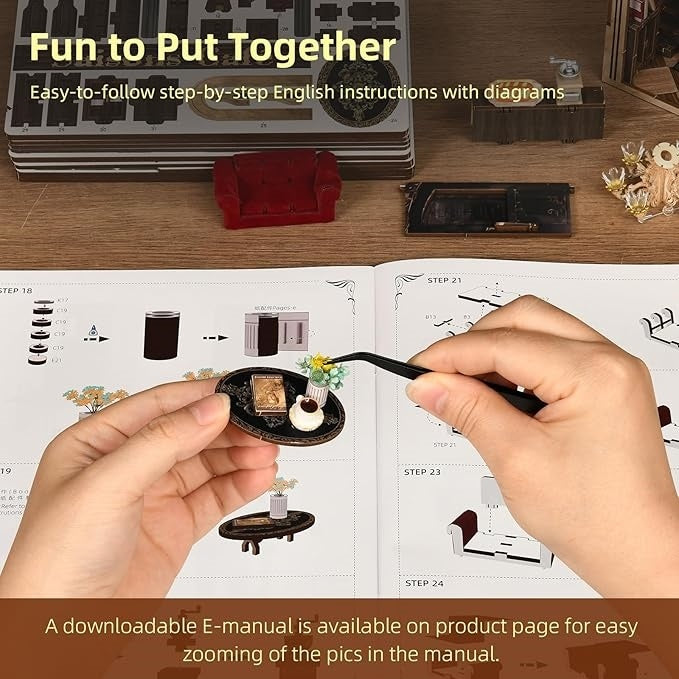 Model building kit with instructions and hands assembling a miniature scene