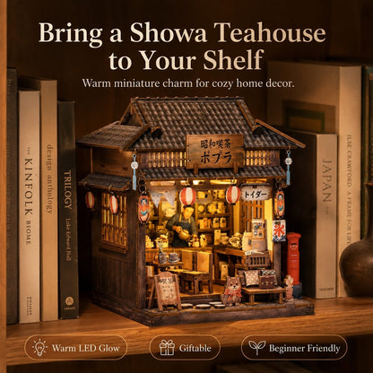 A miniature Japanese tea house shelf decor set displayed on a wooden shelf among books. The product features a detailed dark brown wooden structure with a tiled roof, warm yellow LED lighting from within, red lanterns, and Japanese text details.