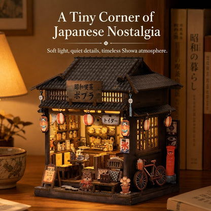 A miniature Japanese-style shop dollhouse with warm glowing interior lights, Japanese lanterns, a bicycle, and tiny shop accessories, displayed on a wooden table with books and a lamp in the background. Text at the top reads 'A Tiny Corner of Japanese Nostalgia'.