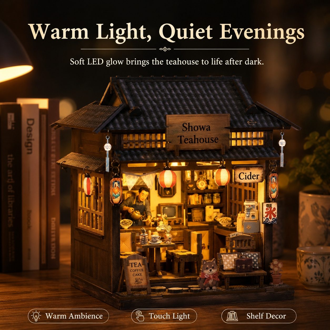 A miniature wooden tea house night light with warm LED glow, displayed on a wooden surface with books and a plant in the background. The sign reads 'Showa Teaouse' and includes labels for 'Tea', 'Coffee', and 'Cider'.