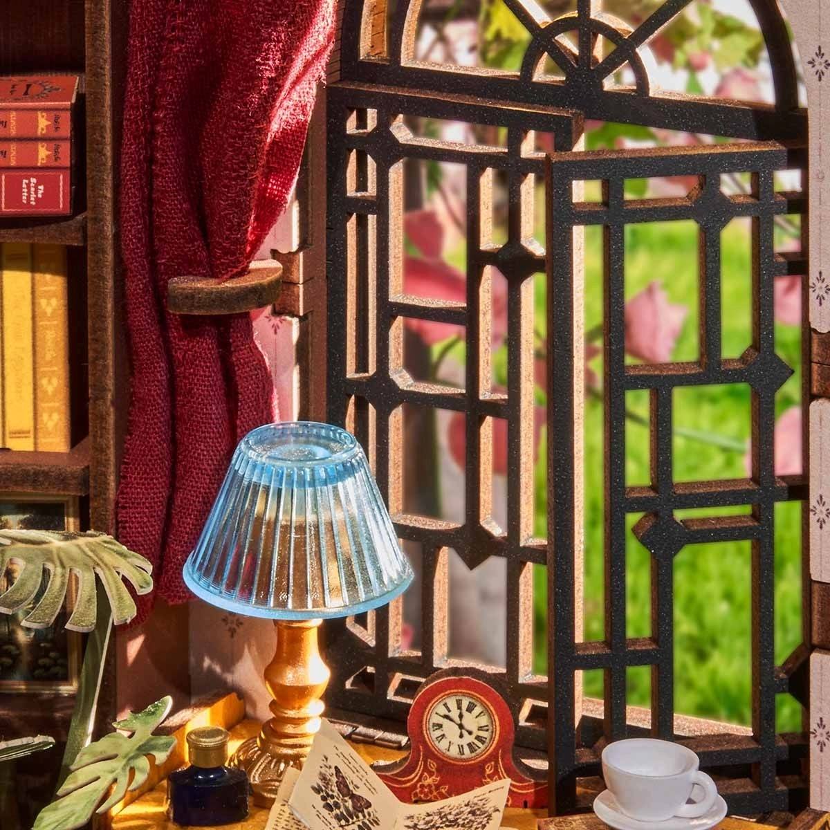 Decorative setup with a miniature small lamp, cup, and books against a blurred natural background