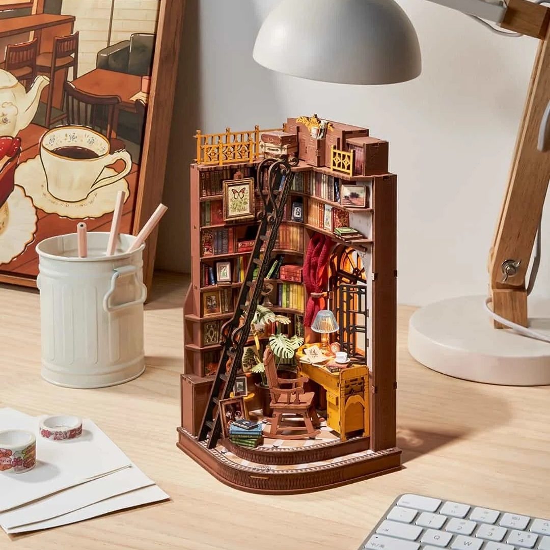 Wooden book nook model of a bookshelf with various items on a desk
