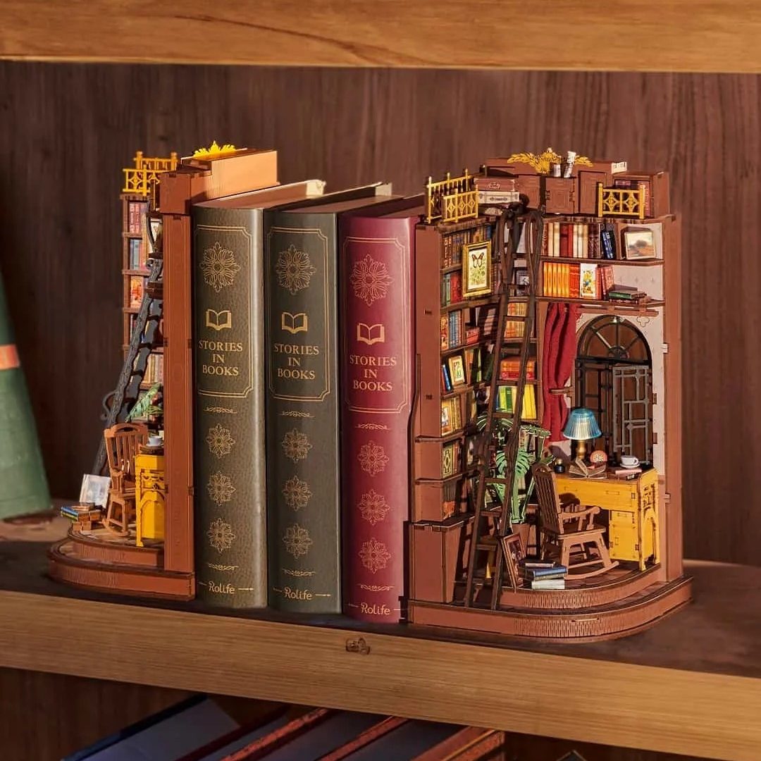 Miniature book nook model of a bookshelf with books and decorative elements on a wooden surface.