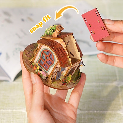 Miniature house model with a hand holding a red component labeled 'snap fit'.