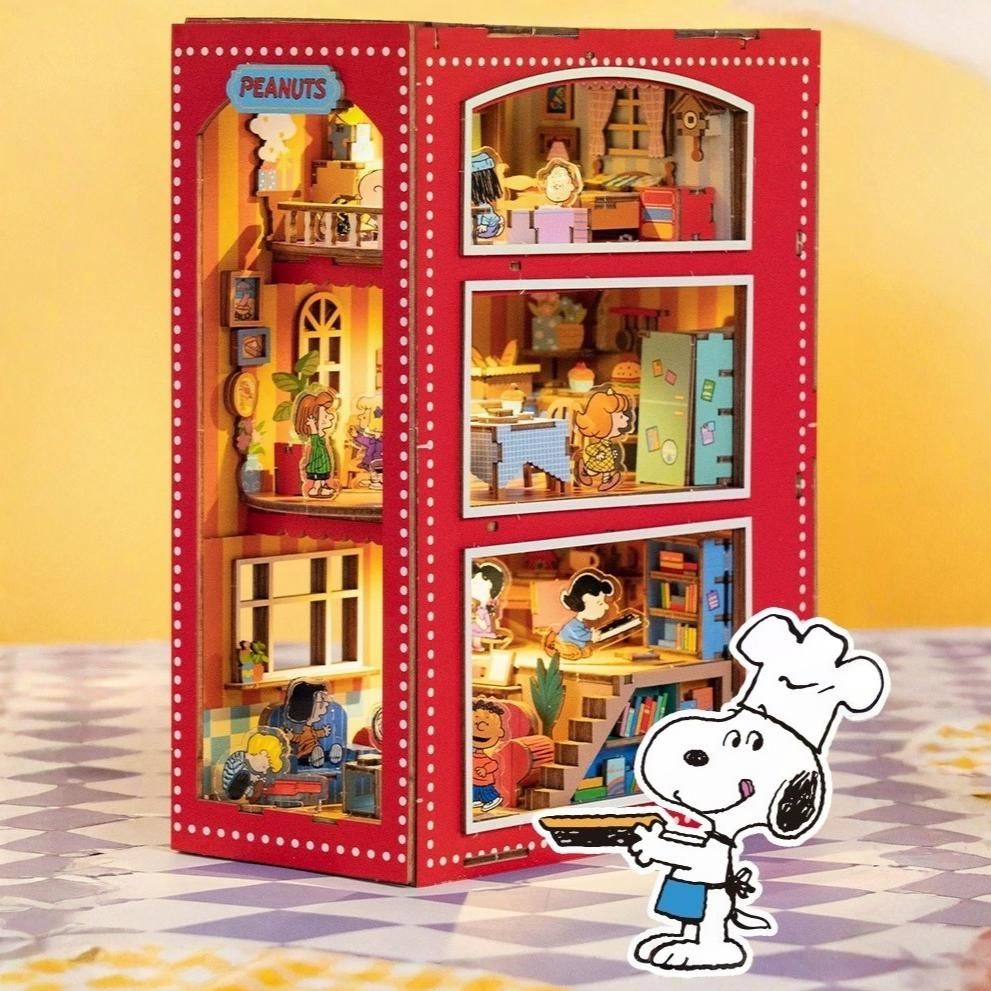 Red book nook with a miniature model of a Peanuts' house interior, featuring Snoopy in a chef's hat.