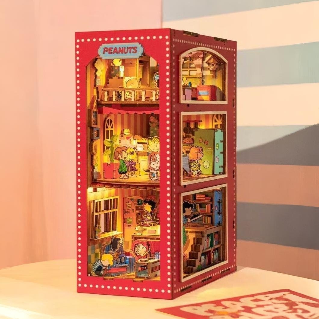 Peanuts-themed miniature bookshelf model in packaging with colorful interior