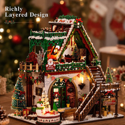 A detailed Christmas house miniature decoration with layered design, featuring a snowy roof, wooden stairs, decorated trees, a snowman figure, and warm glowing lights in a festive holiday setting.