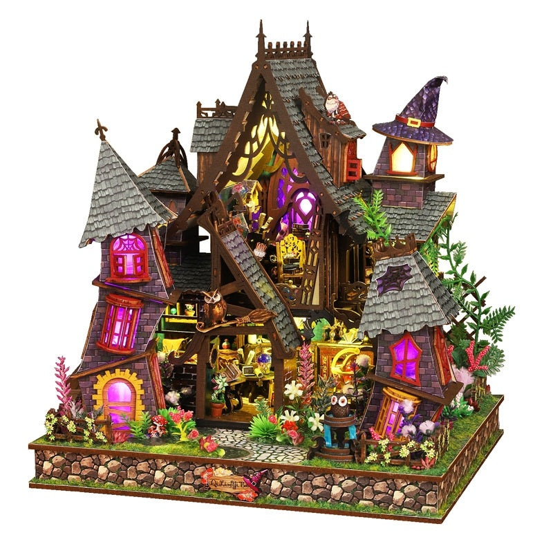 Detailed miniature house model of a fairy tale house with lit windows on a white background