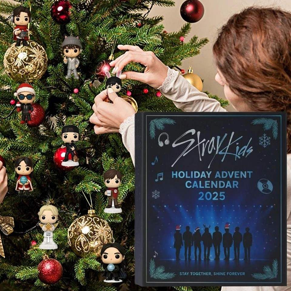 Person decorating a Christmas tree with figurines, next to a Stray Kids holiday advent calendar.