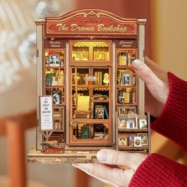 Miniature model of a bookshop named 'The Drama Bookshop' held by a person.