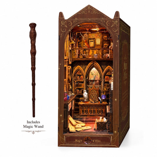 A miniature wizarding library or magic office Book Nook, with a matching carved wooden wand displayed beside it on a white background. The book nook has ornate gold detailing and the words 'Magic Office' on the front, and text below the wand reads 'Includes Magic Wand'.