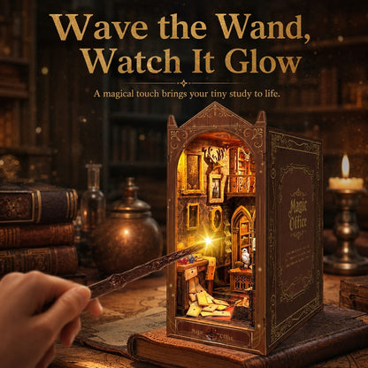 A hand holds a wand in front of an open decorative book-shaped miniature study labeled 'Magic Office,' with warm glowing lights inside. The scene is set on a wooden desk with old books, bottles, and candles in a dim library-like environment.