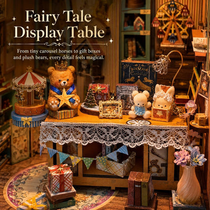 A miniature fairy tale display table dollhouse scene with a lace-covered table holding a teddy bear, plush toys, gift boxes, a carousel, and cozy decorative props in a warm, whimsical room setting.