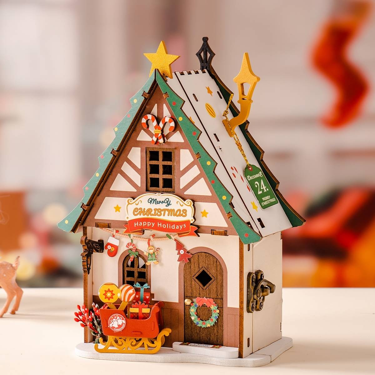 image displaying the assembled Twinkling Christmas House DIY Miniature House Kit in a Christmas-themed table setting