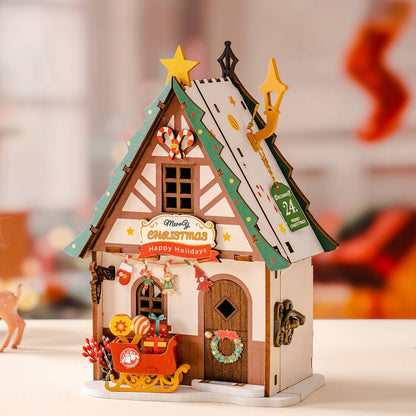 image displaying the assembled Twinkling Christmas House DIY Miniature House Kit in a Christmas-themed table setting