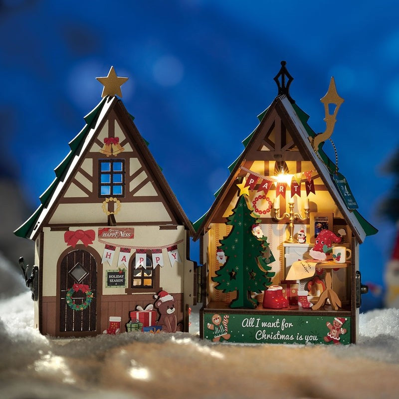 image displaying the flipped-open assembled Twinkling Christmas House DIY Miniature House Kit in a Christmas-themed table setting