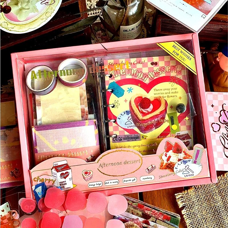 DIY Journaling Kit gift box with stationery items and a card on a wooden surface.