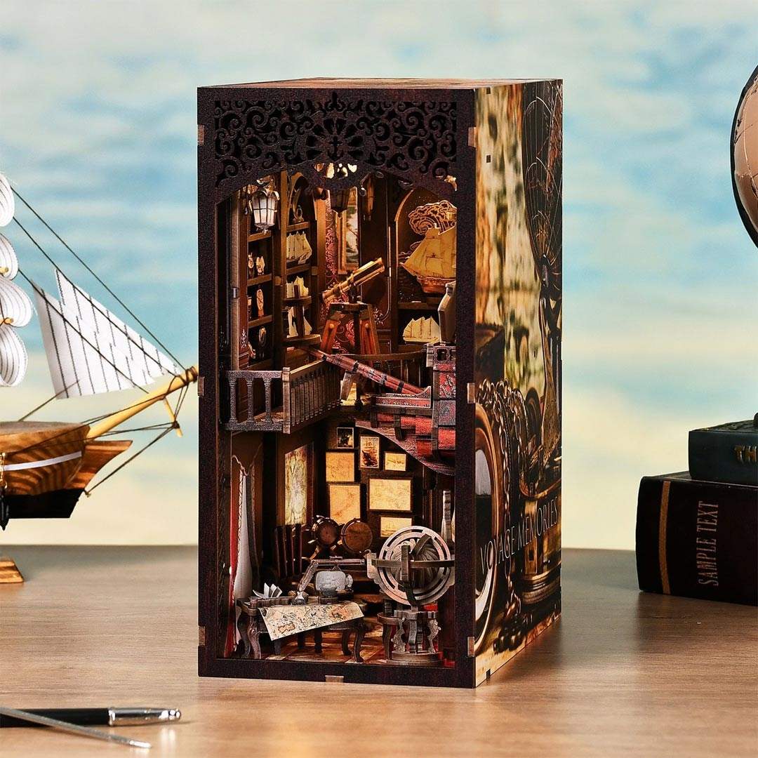 Voyage Memories Book Nook with intricate cut-out designs on a wooden surface with a ship model in the background
