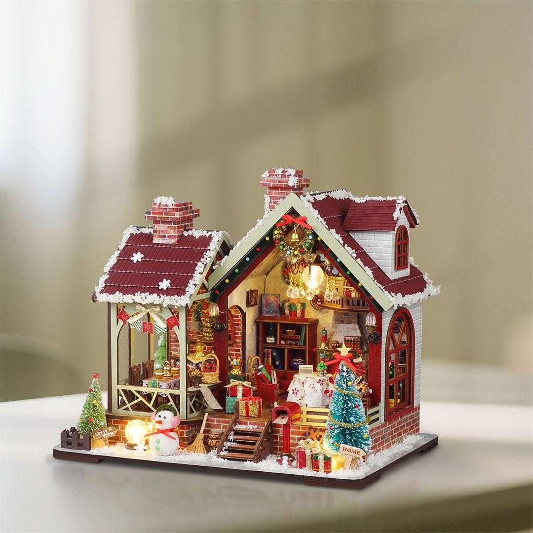 Decorative Christmas house model with lights and ornaments on table