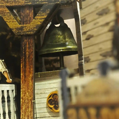 Close-up of a wooden miniauture bell tower with a green glass bell inside, blurred background