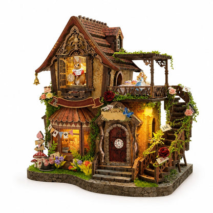 A highly detailed, whimsical miniature dollhouse featuring a multi-story cottage with a rabbit clock, a staircase, a balcony with a tea-time scene, and decorative floral accents, all set on a stone-textured base against a white background.