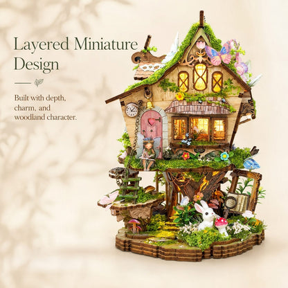 A highly detailed, multi-layered miniature fairy house set against a soft beige background with decorative text on the left. The house features a mossy green roof, warm glowing windows, a pink door, a rustic wooden porch, and various whimsical details like a rabbit figurine, butterflies, and tiny garden elements.