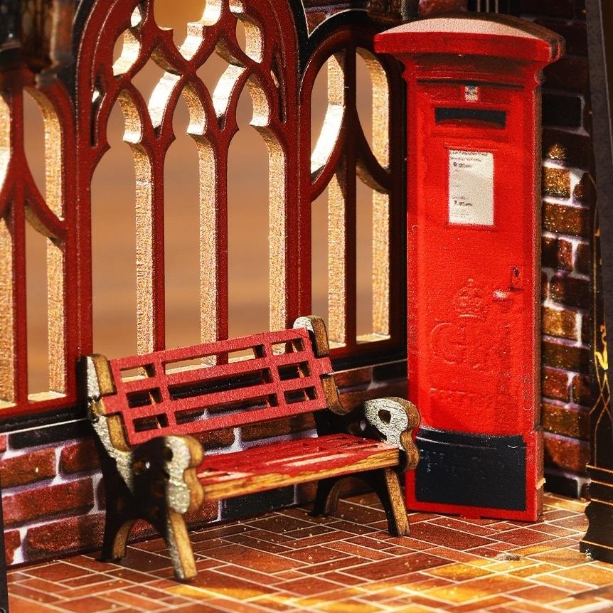 miniature Red bench and postbox in front of a brick wall with decorative arches.
