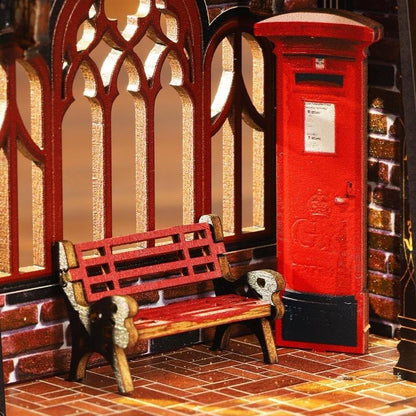 miniature Red bench and postbox in front of a brick wall with decorative arches.
