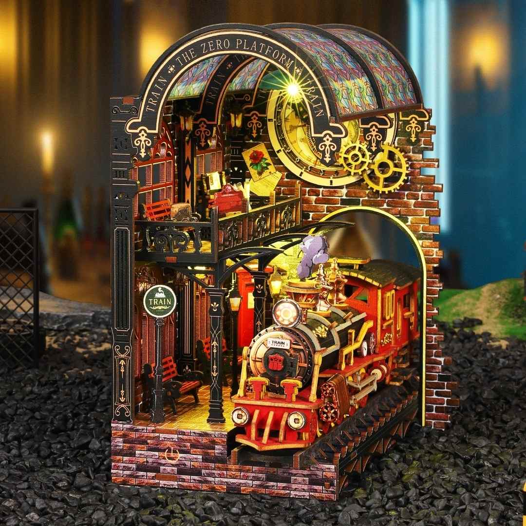 Detailed miniature book nook model of a train station with a steam locomotive, colorful architecture, and decorative elements.